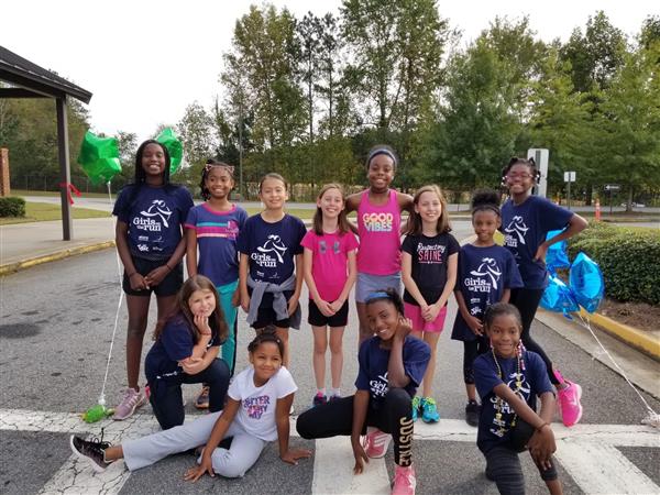 Girls on the Run students posing together on the asphalt